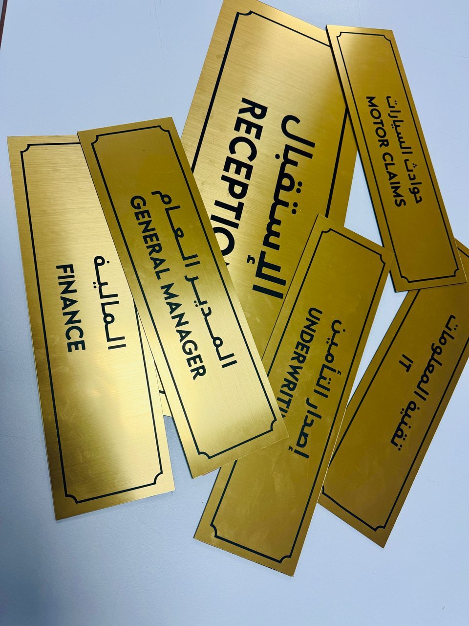 Arabic and English department labels with a gold-coloured finish.