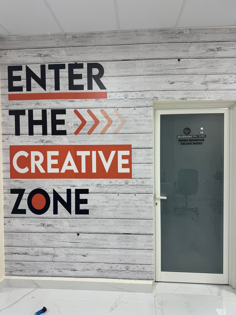 Large lettering and directional graphics beside an office door.
